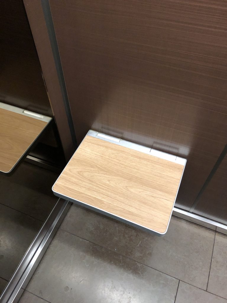 View of a folding seat in an elevator. The seat is folded down for use.
