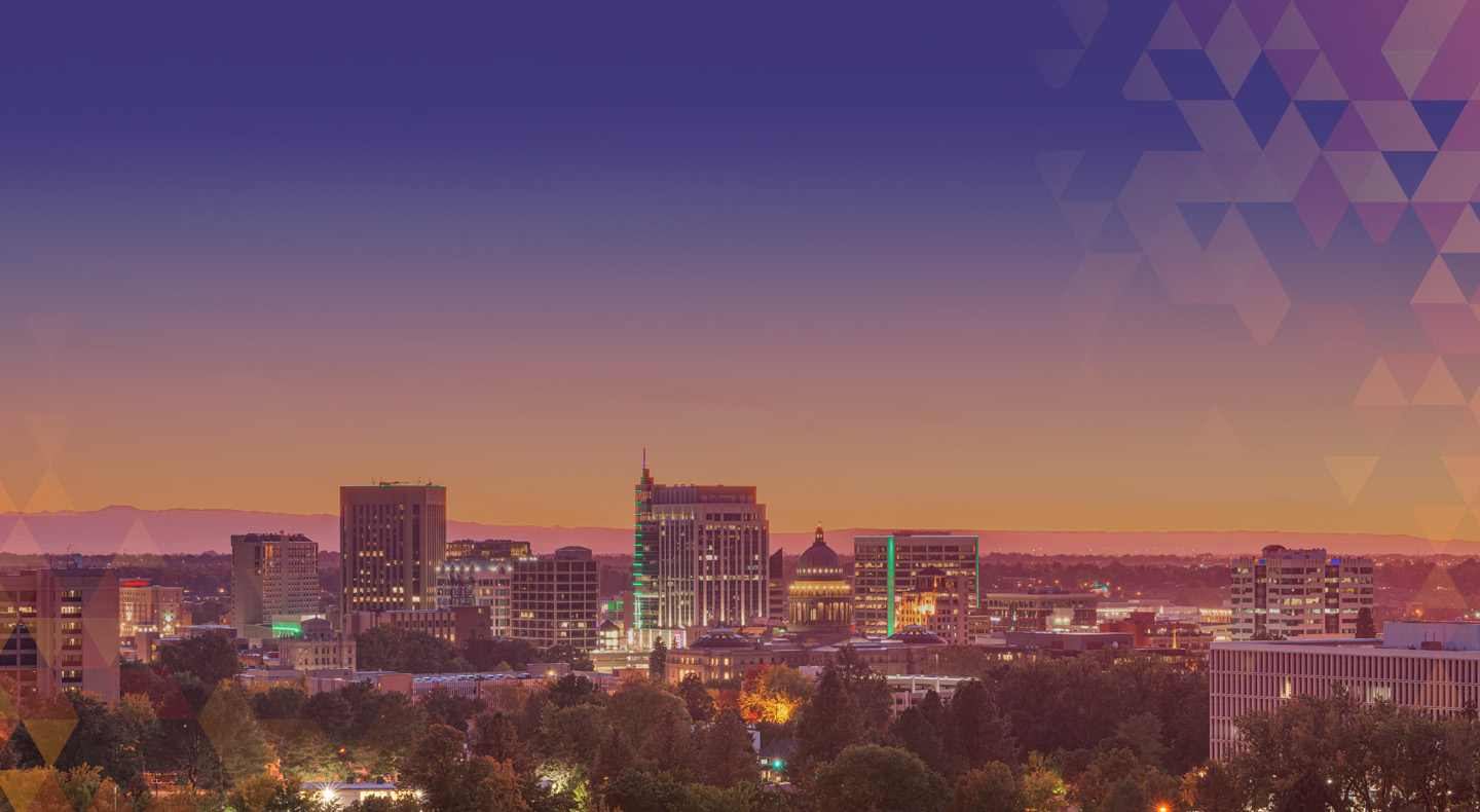 A slightly elevated panoramic view of Boise's glowing city skyline at dusk. The sky is depicted in a top down gradient of deep purple to a muted orange along the flat distant horizon line. Overlaying the sky, in our upper right hand corner, is a geometric triangular mosaic pattern in shades of purple and muted orange. The city features about a dozen mid sized skyscrapers and buildings, including a distinctive domed capitol-like structure in the middle. The foreground is filled with a thick canopy of trees, occasionally lit up by pinpricks of street lights shining through the leaves